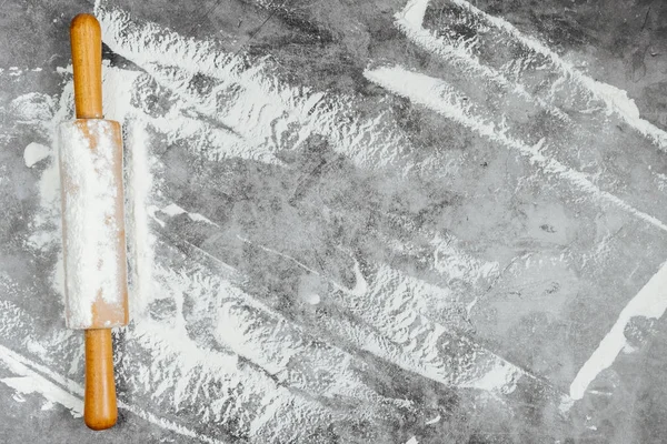 Gri bir arka plan üzerinde oklava ve beyaz un. Fırında menü, tarifi, ev yapımı pasta konsepti. Metin için boş alan. Düz döşeme, üst görünüm, metniniz için kopyalama alanı.