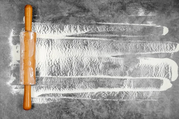 Gri bir arka plan üzerinde oklava ve beyaz un. Metin için boş alan. Düz döşeme, üst görünüm, metniniz için kopyalama alanı.