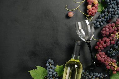 Bir şişe, şarap bardakları, taze üzüm ve siyah arka plan üzerinde yaprakları. Düz döşeme, üst görünüm, kopyalama alanı. Şarap barı, şaraphane, şarap tatma konsepti