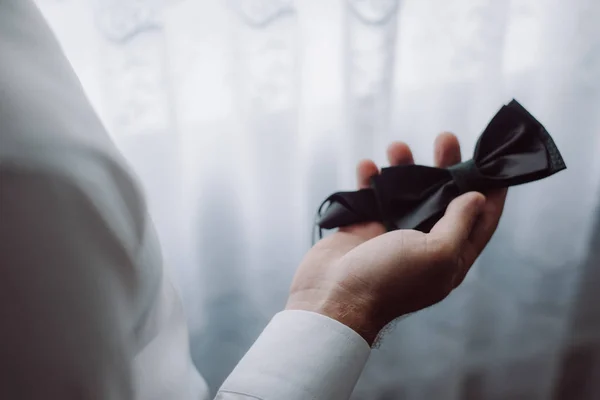 Imagen horizontal de la corbata de mariposa oscura en las manos de un hombre. Detalles de boda . —  Fotos de Stock