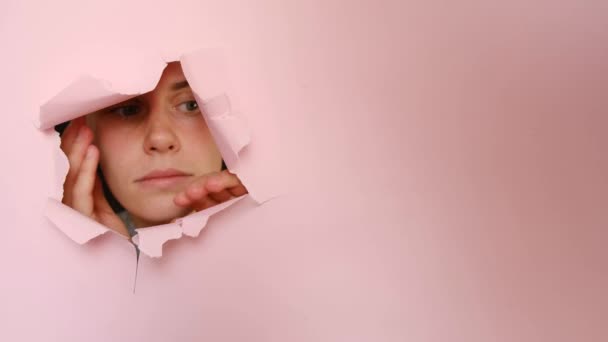 Verbaasde Jonge Vrouw Staart Door Gat Roze Papier Opent Mond — Stockvideo