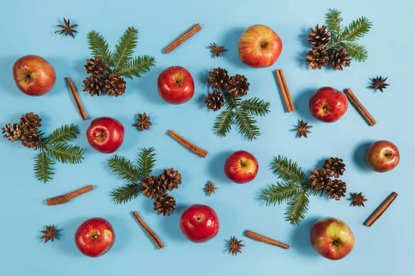 Noel veya kış kompozisyonu. Çerçeve köknar ağacı dalları, çam, kırmızı elma ve tarçın pastel mavi arka plan üzerinde yapılmıştır. Noel, kış, yeni yıl konsepti. Düz döşeme, üst görünüm, kopyalama alanı — Stok fotoğraf