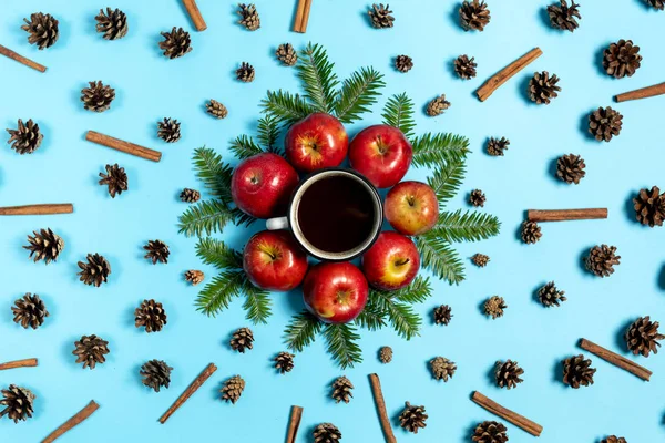 Kış kompozisyonu. Çerçeve köknar ağacı dalları, çam, kırmızı elma, fincan kahve ve tarçın pastel mavi arka plan üzerinde yapılmıştır. Sonbahar, sonbahar, kış konsepti. Düz döşeme, üst görünüm, kopyalama alanı — Stok fotoğraf