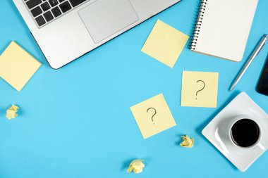 Yapışkan notlardaki soru işareti, defter, fincan kahve, telefon, mavi arka plandaki kalem. Faq konsepti. Müşterilerle çalışmak. İşte sorunlar var. Düz konum, üst görünüm, kopyalama alanı