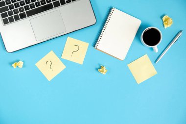 Yapışkan notlardaki soru işareti, defter, fincan kahve, dizüstü bilgisayar ve mavi arka plandaki kalem. Faq konsepti. Müşterilerle çalışmak. İşte sorunlar var. Düz konum, üst görünüm, kopyalama alanı
