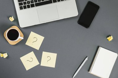 Yapışkan notlardaki soru işareti, defter, fincan kahve, telefon, gri arka plandaki kalem. Faq konsepti. Müşterilerle çalışmak. İşte sorunlar var. Düz konum, üst görünüm, kopyalama alanı