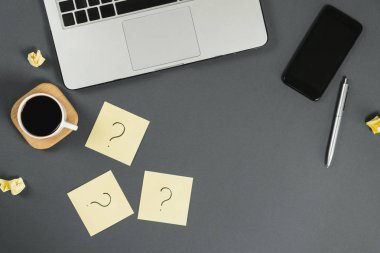 Sorular, kararlar. Yapışkan notlardaki soru işareti, defter, fincan kahve, telefon, gri arka plandaki kalem. Faq konsepti. Müşterilerle çalışmak. İşte sorunlar var. Düz konum, üst görünüm, kopyalama alanı