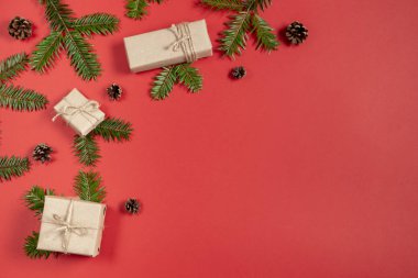 Noel ya da kış kompozisyonu. Köknar ağacı dallarından yapılmış çerçeve, kırmızı arkaplanda çam ağacı. Noel, kış, yeni yıl konsepti. Düz konum, üst görünüm, kopyalama alanı