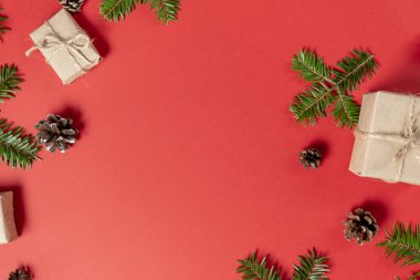 Noel kompozisyonu. El yapımı hediye kutuları el işi kağıt, ağaç dalları, kırmızı arka planda çam ağacı. Düz konum, üst görünüm, kopyalama alanı