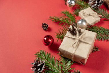 Noel ya da kış kompozisyonu. El yapımı hediye kutuları, köknar ağacı dallarından yapılmış el yapımı kağıt, çam ağacı ve tarçınlı pastel kırmızısı arka planda. Düz konum, üst görünüm, kopyalama alanı