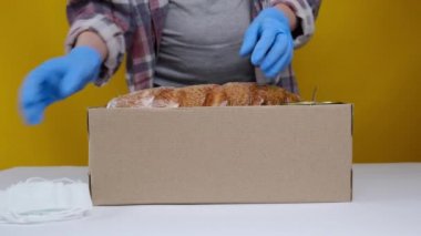 Koruyucu tıbbi eldivenli kadının ön tarafı yiyecek dolu kutuları açıyor. Coronavirus salgını sırasında evden ve sosyal mesafelere çalışmak için teslimat hizmeti. Bağış konsepti
