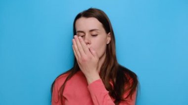 Sinirli genç esmer kadının portresi, nefesini kontrol ediyor, kötü bir koku alıyor, burnunu çimdikliyor, süveter giyiyor, mavi stüdyo arka planında izole edilmiş. Kötü koku konsepti.