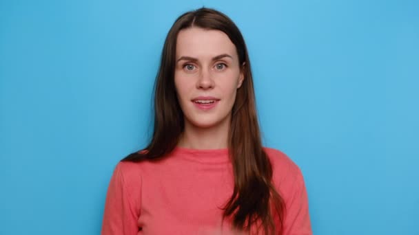 具有惊喜表情的积极快乐的年轻女性的画像 标明广告或促销内容的空白复制空间 穿着红色毛衣 在蓝色的工作室背景下摆姿势 — 图库视频影像