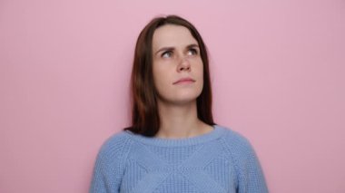 Düşünceli bir kadının portresi şüpheyle yukarı bakar, düşüncelerle, şüphelerle aklında toplanmaya çalışır, pembe stüdyo arka planında durur, süveter giyer. Düşüncelere dalmış dalgın tatlı kız