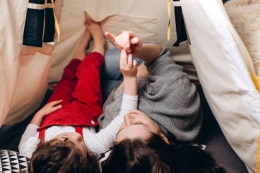 Sevimli, küçük kızıyla birlikte uzanan esmer bir annenin çocuk odasındaki çadırda parmaklarıyla oynayıp saymasını, birlikte eğlenmesini ve vakit geçirmesini.