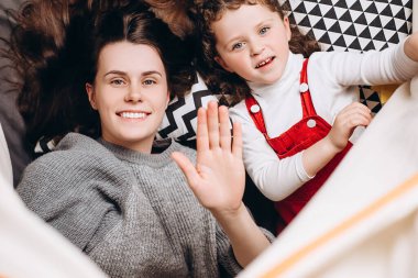 Gülümseyen genç anne ve sevimli küçük kız çocuğunun çadırda yatıp sohbet ederken görüntülerini izleyip kahkahalarla gülüyorlar. İnternet sohbetlerinin tadını çıkarıyorlar. Web kameralarına bakıyorlar.