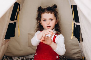 Sevimli küçük kız blogcu kamerayla konuşuyor ve evde parmaklarını sayıyor. Küçük çocuk vlogcu el sallıyor. Kameralı çocuğa bakıyor.