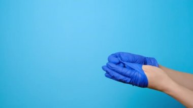 Tanımlanamayan genç bir kadın, tıbbi eldivenlerini çıkarıp çöpe atıyor. Reklam için fotokopi çekilen mavi bir arka plan. Virüs salgınının sonu kavramı