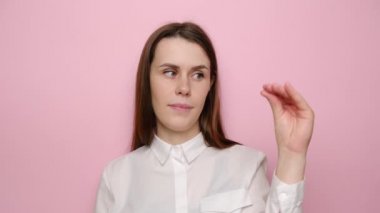 Beyaz gömlekli, pembe stüdyo arka planında soyutlanmış, gösteriş yapan sıkıcı esmer kadın portresi. İnsanlar samimi duygular, yaşam tarzı konsepti