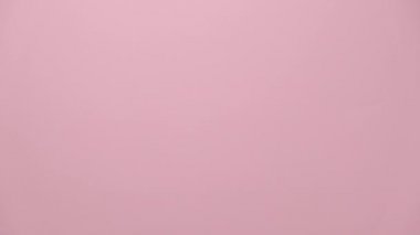 Güzel kadın ellerinin kalp sembolü yaptığı, pembe stüdyo arka planında izole edilmiş, reklam için fotokopi alanı olan bir yer. Aşk ve vücut dili kavramı