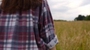 Şapkalı, siluet görünümlü genç bir kadın çayırda yürüyor ve arka plandaki yaz dağı, gençlik ve mutlulukta kollarını havaya kaldırıyor. Gerçek vahşi yaşam tarzını keşfet. Seçici odak