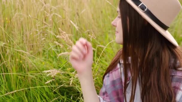 梦幻般的年轻女子头戴礼帽 在阳光下欢快地嗅着新鲜的青草 快乐的浪漫女子在仙境中微笑 令人惊奇的大气时刻 — 图库视频影像