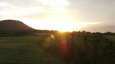 Güzel, ilham verici destansı drone görüntüleri, kozalaklı ağaçlar ve kırsal alanda gün batımına karşı otlaklarla kaplı tepelik arazinin nefes kesici görüntüsü. Gezgin şehvet hedefi