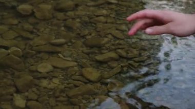 Tanımlanamayan dişinin nazikçe elini yaban dağları nehrinin su yüzeyine değdir. Doğayla barışçıl ve düşünceli bir bağ. Meditasyon ilhamı kavramı