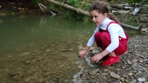 Nahaufnahme Von Niedlichen Kleinen Vorschulmädchen Mit Rotem Outfit Werfen Kieselsteine — Stockvideo