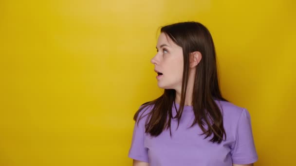 興奮若いです女性指して指によってコピースペース驚くべき販売 驚くべき幸せなブルネットの女の子示す広告格安オファー 服Tシャツ 黄色のスタジオの背景に隔離された — ストック動画