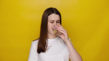 Esmer kadın buzlu su içiyor ve aniden korkunç bir diş ağrısı çekiyor. Hassas diş ve çürüklerin acısı. Stüdyonun sarı arka planında fotokopi alanı ile izole edilmiş. Diş sorunlarını kavra