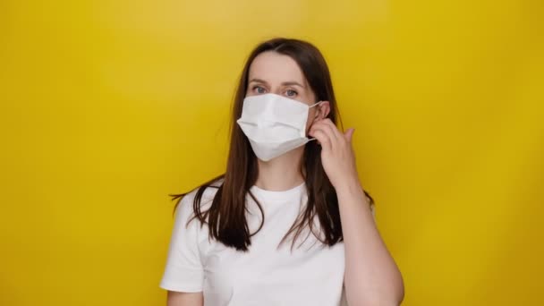 Νεαρή Μελαχρινή Γυναίκα Λευκή Ιατρική Μάσκα Ποζάρει Κίτρινο Φόντο Στούντιο — Αρχείο Βίντεο