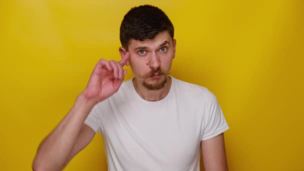 Σοκαρισμένος Νεαρός Άνδρας Απομονωμένος Κίτρινο Φόντο Στούντιο Δείχνει Ηλίθια Χειρονομία — Αρχείο Βίντεο