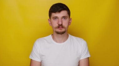 Delikanlının portresi el işareti ve göz kırparak öneriyi onaylar gibi, beyaz tişört giymiş, sarı stüdyo arka planında kopya alanı olan adam tamamen katılıyor ve destekliyor.