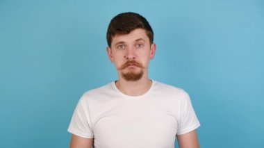 Genç adam ellerini yana uzatıyor, omuz silkiyor, soruya cevap veremiyor, hiçbir fikri yok, beyaz tişört giyiyor, arka planda mavi bir stüdyo ve fotokopi alanı var. İnsanların duygu kavramı