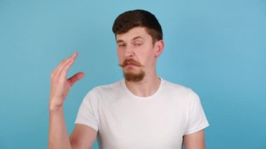 Saçma sapan hareketler yapan, dedikoducu, beyaz tişörtlü, pastel mavisi arka planda kopyalanmış bir genç adam. Sinirli adam bla-bla hareketi yapıyor.