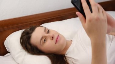 Rahatlamış genç bir kadın sabah sosyal ağ haberlerini okur, yeni cep telefonu uygulamasını sever, sakin gülümseyen kız ajanda planlama gününü kontrol eder, online ya da kadın kullanıcı flörtü yapan kişi kendi portresini yapar