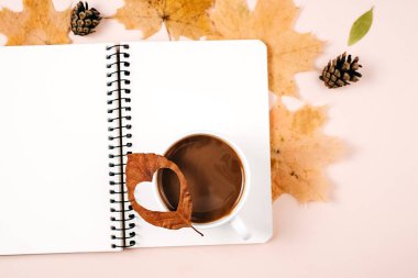 Sonbahar kompozisyonu. Kurumuş çeşitli yapraklar, sütlü kahve fincanı, kozalaklar ve reklam için pembe stüdyo arka planında not defteri. Sonbahar, sonbahar, Şükran Günü konsepti. Düz yatış, üst görünüm