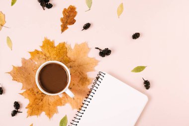 Sonbahar düzlüğü, üstte uzanan kahve fincanı, kurumuş yapraklar ve pembe arka plandaki defter fotokopi alanı minimal stil. Feminen blog sosyal medya için sonbahar şablonu. Yaratıcı bileşim