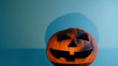 Ürkütücü turuncu balkabağı üzerine sarı ışık, reklam için fotokopi alanı olan mavi stüdyo arka planında izole edilmiş. Cadılar Bayramı sezonu kavramı