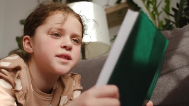 Nærbillede Nysgerrig Charmerende Lille Barn Pige Liggende Komfortabel Sofa Læse – Stock-video
