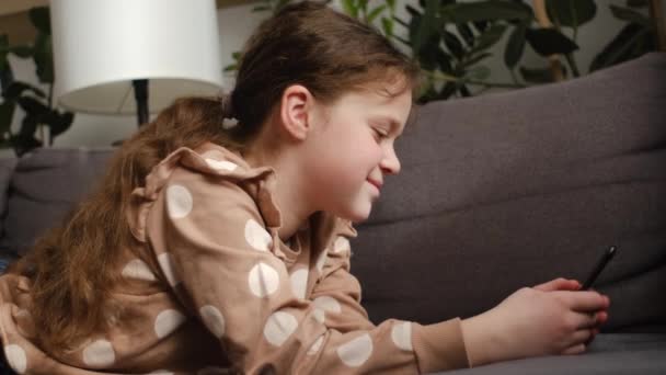 Joyeux Petit Enfant Fille Tapant Sur Smartphone Assis Sur Canapé — Video