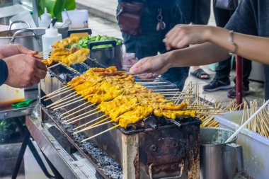 En ünlü satay domuz eti ızgara şiş bambu sopayla tatlı fıstık sos ile servis ve turşu Tayland'da sokak gıda pazarında satmak. Seçici odak