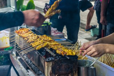En ünlü satay domuz eti ızgara şiş bambu sopayla tatlı fıstık sos ile servis ve turşu Tayland'da sokak gıda pazarında satmak. Seçici odak