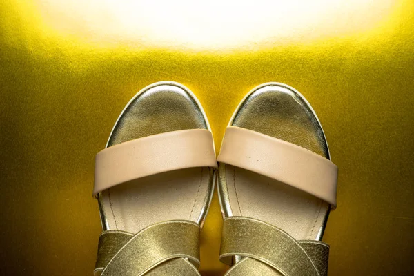 Стильне жіноче взуття лежить на золотому фоні — стокове фото