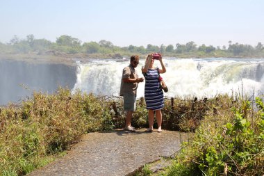 Hwange, ZIMBABWE - 3 Ekim 2018 Victoria Falls Ulusal Parkı 'nda turistler. Zambezi Nehri 'nin güney ve doğu kıyısında, dünyaca ünlü Victoria Şelalesi bölgesinde yer alan park.