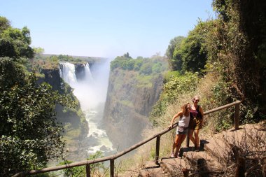 Hwange, ZIMBABWE - 3 Ekim 2018 Victoria Falls Ulusal Parkı 'nda turistler. Zambezi Nehri 'nin güney ve doğu kıyısında, dünyaca ünlü Victoria Şelalesi bölgesinde yer alan park.