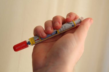 Epinephrine Auto injector ready to use. It is a medical device for injecting doses of epinephrine or adrenaline through a needle into a patient suffering an allergy clipart