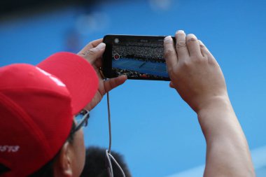 Melbourne, Avustralya - 27 Ocak 2019: Tanımlanamayan seyirci 2019 Melbourne Park yılında Avustralya Açık Tenis maçında sırasında fotoğraf çekmek için cep telefonunu kullanır