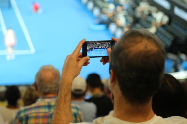 Melbourne, Avustralya - 27 Ocak 2019: Tanımlanamayan seyirci 2019 Melbourne Park yılında Avustralya Açık Tenis maçında sırasında fotoğraf çekmek için cep telefonunu kullanır